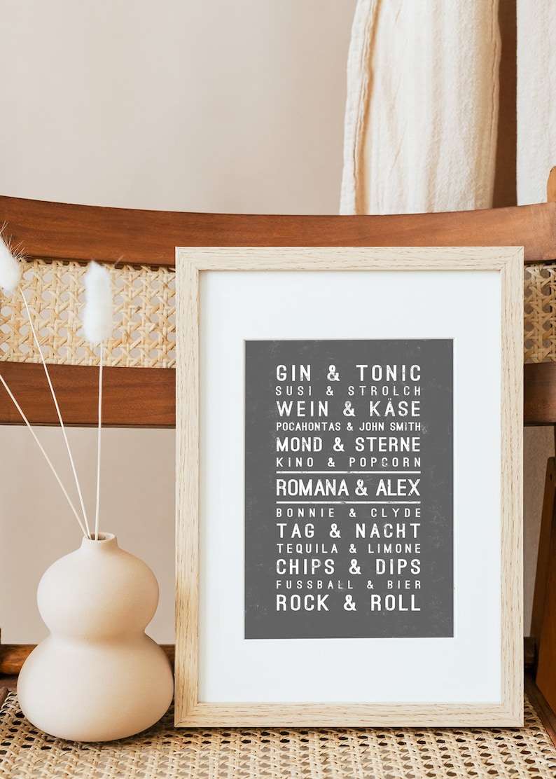 May include: A framed print with a black background and white text. The text lists various pairs of words in German, such as "Gin & Tonic", "Susi & Strolch", and "Wein & K&auml;se".