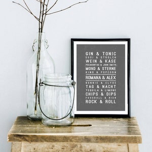 May include: A black and white framed print with a gray background and white text. The text lists various pairs of words, such as "Gin & Tonic", "Susi & Strolch", "Wein & K&auml;se", "Pocahontas & John Smith", "Mond & Sterne", "Kino & Popcorn", "Romana & Alex", "Bonnie & Clyde", "Tag & Nacht", "Tequila & Limone", "Chips & Dips", "Fussball & Bier", and "Rock & Roll".