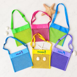 May include: Six mesh bags with adjustable shoulder straps in green, pink, blue, light blue, yellow, and purple. Three bags feature personalized names: Madi with a seahorse, Emma with a pineapple, and Lillie with a dolphin icon printed on them.