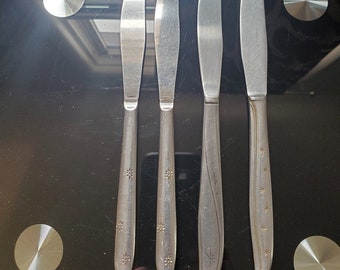 May include: Four silver dinner knives with star-shaped designs on the handles.