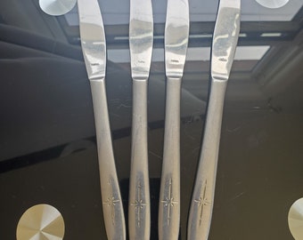 May include: Four silver dinner knives with a star design on the handle. Each knife has the word "JAPAN" engraved on the blade.