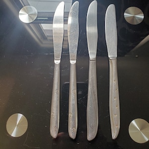 Puede incluir: Cuatro cuchillos de cena de plata con diseños en forma de estrella en los mangos.