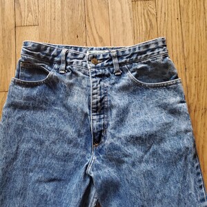 May include: A pair of light blue acid wash denim jeans with a button fly and five pockets.