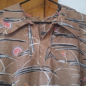 May include: A brown and white patterned dress with a collar and a zipper closure. The dress has a floral design with black lines and white accents.