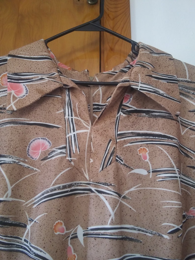 May include: A brown and white patterned dress with a collar and a zipper closure. The dress has a floral design with black lines and white accents.