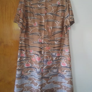 May include: A brown dress with a short sleeve and a floral print. The print features pink, blue, and white flowers on a brown background.