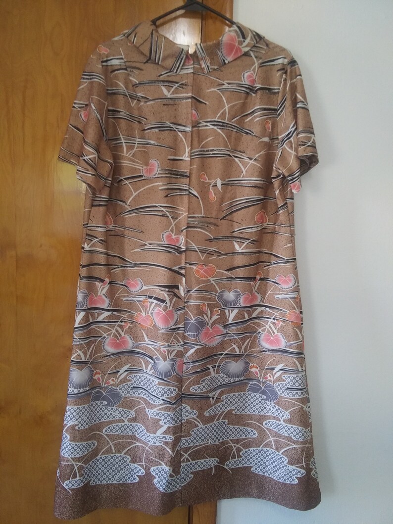 May include: A brown dress with a short sleeve and a floral print. The print features pink, blue, and white flowers on a brown background.