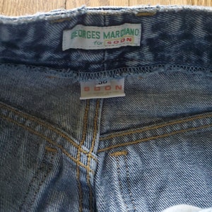 May include: Light blue denim jeans with a green label that reads "Georges Marciano for SOON" and a white label that reads "SOON 30".