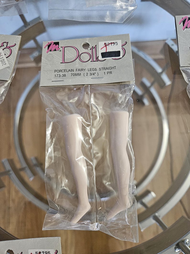 May include: A package containing two porcelain fairy doll legs. The legs are straight and measure 2 3/4 inches (70mm) in length. The packaging includes the text "Porcelain Fairy Legs Straight" and the brand name "Ms. Dolls".