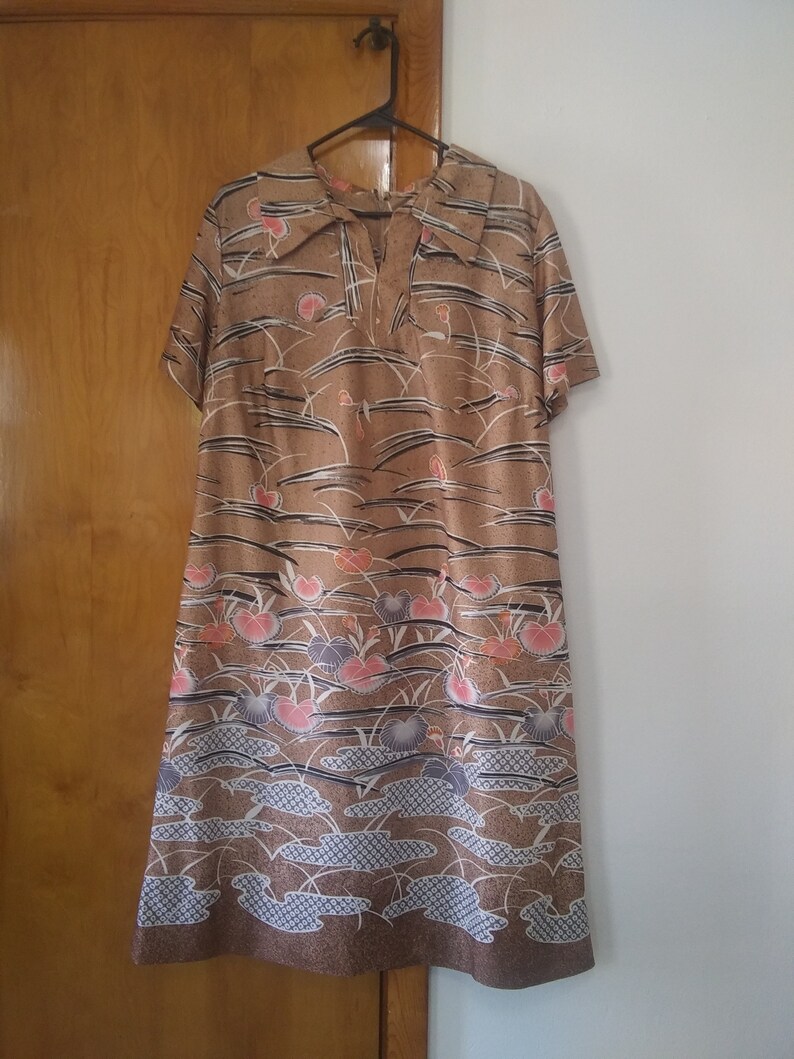 May include: A brown midi dress with a floral print featuring pink, white, and blue flowers. The dress has a V-neckline and short sleeves.