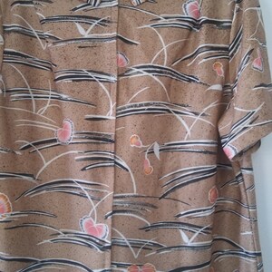 May include: A brown dress with a white and black floral pattern. The dress has a short sleeve and a collared neckline.