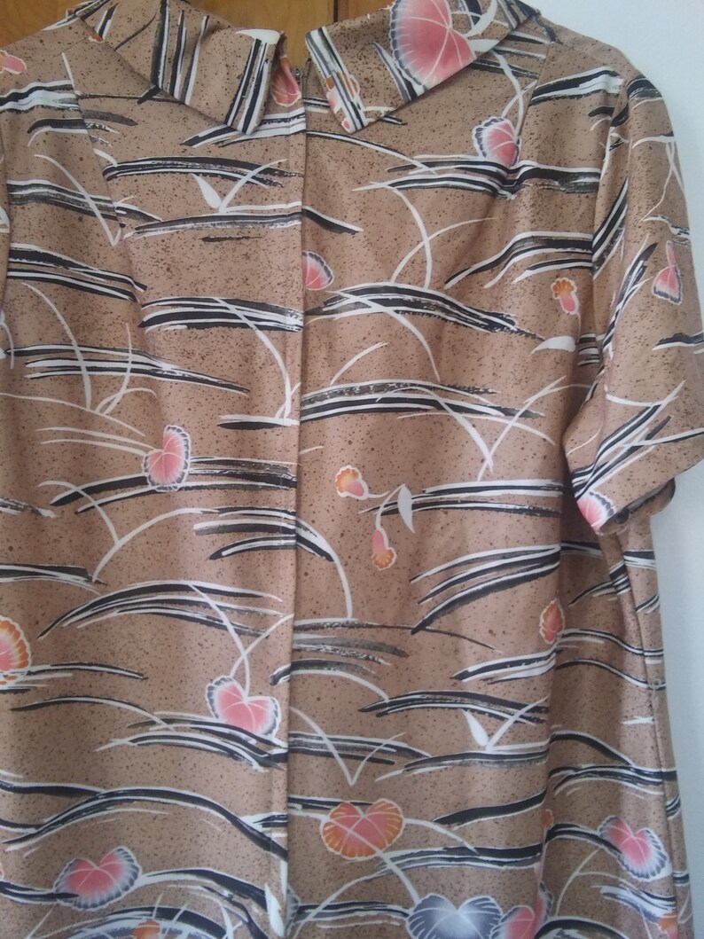 May include: A brown dress with a white and black floral pattern. The dress has a short sleeve and a collared neckline.