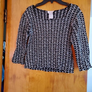 May include: Black and white patterned long-sleeved shirt with a scoop neck. The shirt is hanging on a hanger and has the word "wrapps" on the tag.