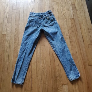 May include: Light blue denim jeans with a faded wash and a triangular logo on the back pocket.