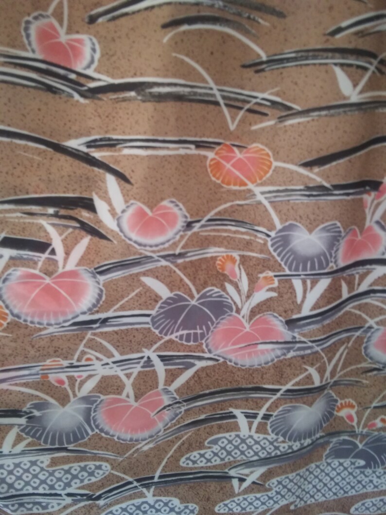 May include: A brown fabric with a repeating pattern of pink, orange, and gray flowers. The flowers are stylized and have a watercolor effect. The background is a light brown with a subtle texture.