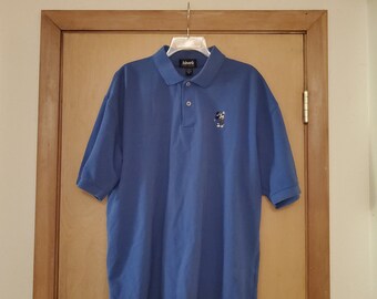 May include: A blue short-sleeved polo shirt with a small embroidered logo on the left chest. The logo is a black and white image of a bear wearing a hat.