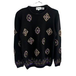 Può includere: Maglione nero con un motivo geometrico di paillettes dorate e viola. Il maglione ha un collo rotondo e maniche lunghe. L'etichetta del marchio recita "Corducci".