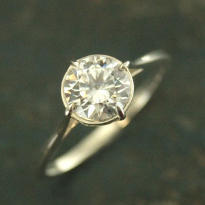 May include: A silver ring with a large, clear, round diamond.