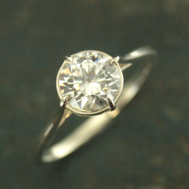 May include: A silver ring with a large, clear, round diamond.
