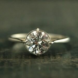 May include: A silver engagement ring with a large, round, clear diamond.