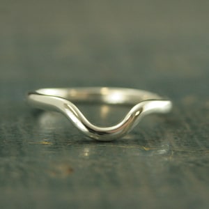 May include: A silver ring with a wavy, curved design. The ring is smooth and polished.