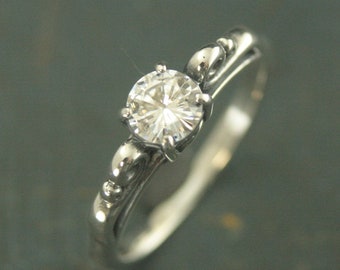 May include: A silver ring with a single, round, clear gemstone set in a decorative, ornate setting.