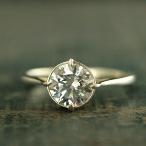 May include: A silver engagement ring with a large, round, clear diamond.