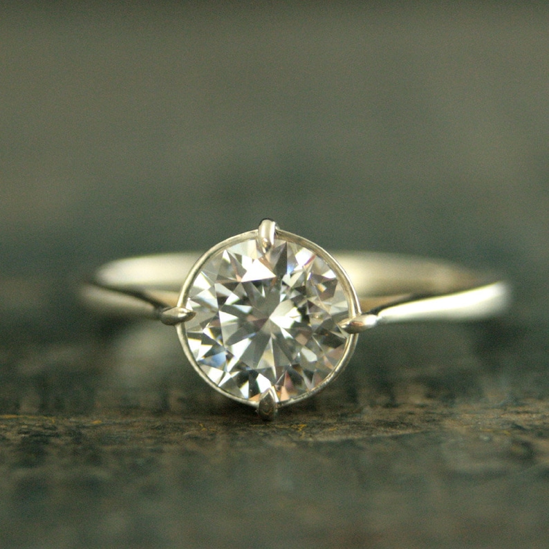May include: A silver engagement ring with a large, round, clear diamond.