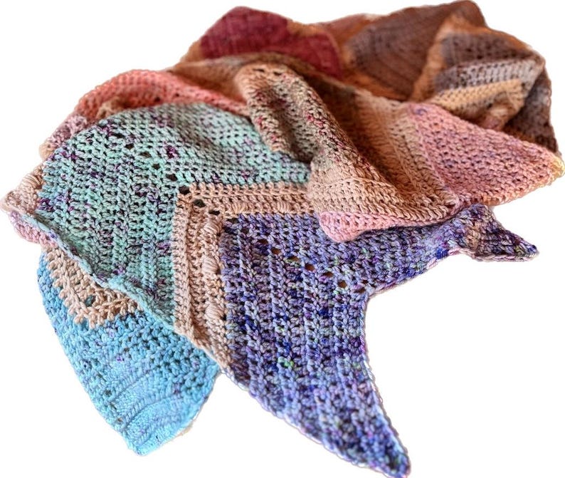 May include: A triangular crochet shawl featuring a variegated color palette of light blue, mint green, soft pink, and deep purple. The textile displays a textured stitch pattern with subtle speckles throughout the yarn, creating a soft gradient.