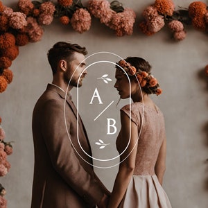 Peut inclure: Un couple se tient face à face devant un mur décoré d'une guirlande florale. La femme porte une couronne de fleurs et une robe couleur blush. L'homme porte un costume marron. Un graphique ovale blanc avec les initiales "A/B" est superposé à l'image.