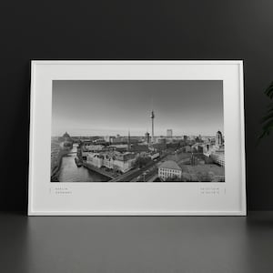Puede incluir: Impresi&oacute;n enmarcada en blanco y negro de Berl&iacute;n, Alemania. El paisaje urbano incluye la Torre de la Televisi&oacute;n, edificios y un r&iacute;o. La impresi&oacute;n tiene el texto "Berlin Germany" y coordenadas.