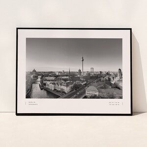 Puede incluir: Impresi&oacute;n enmarcada en blanco y negro de Berl&iacute;n, Alemania. La imagen captura una vista panor&aacute;mica de la ciudad, incluyendo la ic&oacute;nica Torre de Televisi&oacute;n y otros puntos de referencia. La impresi&oacute;n incluye el nombre de la ciudad y coordenadas.
