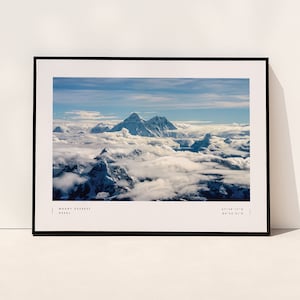 Pu&ograve; includere: Una fotografia incorniciata del Monte Everest, una cima montuosa innevata, che si erge sopra un mare di nuvole bianche. L'immagine &egrave; scattata da una prospettiva aerea, mostrando la maestosa scala della montagna. Il testo "MOUNT EVEREST NEPAL 27&deg;59'17"N 86&deg;55'31"E" &egrave; stampato nella parte inferiore dell'immagine.
