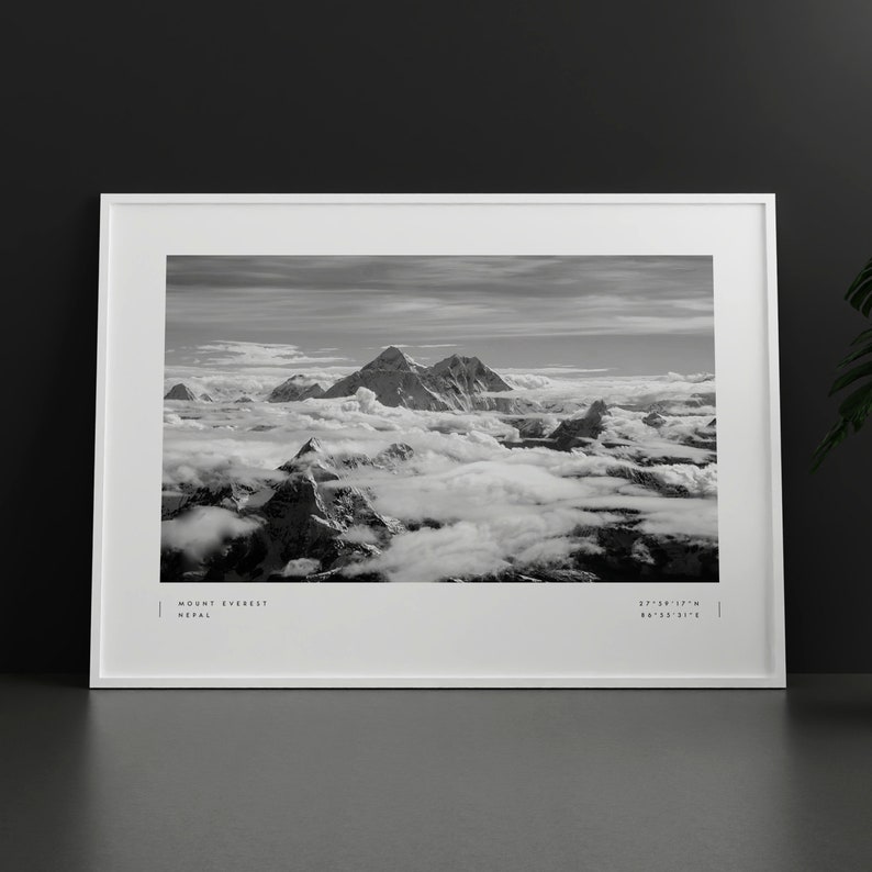 Pu&ograve; includere: Una fotografia in bianco e nero del Monte Everest, la montagna pi&ugrave; alta del mondo, con cime innevate e nuvole sullo sfondo. Il testo "MOUNT EVEREST NEPAL" e "27&deg;59'17"N 86&deg;55'31"E" &egrave; stampato nella parte inferiore dell'immagine.