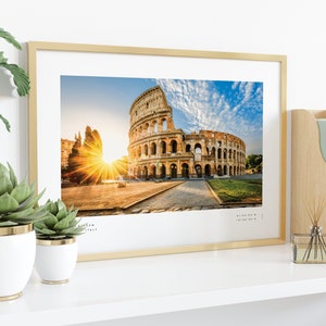 May include: A framed photograph of the Colosseum in Rome, Italy. The photo shows the ancient amphitheater with a bright sunrise in the background. The frame is gold and has a white mat.