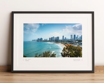 May include: A framed photograph of the Tel Aviv skyline, showing a city with tall buildings along a coastline with blue water and a sandy beach. The photo includes the coordinates 32°04'03"N 34°45'00"E.