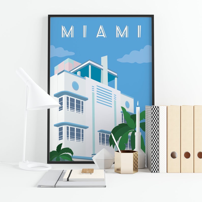May include: A poster with the word "MIAMI" in white letters against a blue sky. The poster features a white art deco building with blue accents and palm trees.