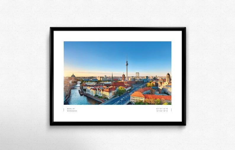 Puede incluir: Fotograf&iacute;a panor&aacute;mica enmarcada de Berl&iacute;n, Alemania, con la ic&oacute;nica Torre de Televisi&oacute;n, el r&iacute;o Spree y arquitectura hist&oacute;rica bajo un cielo azul claro. La impresi&oacute;n incluye el nombre de la ciudad y sus coordenadas.