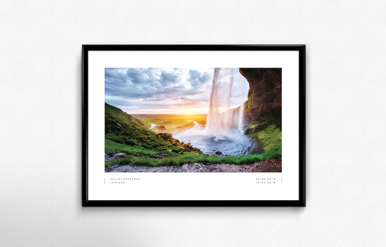 Op de afbeelding: Een panoramische foto van een waterval die over een klif in IJsland stort. De waterval wordt omringd door weelderige groene vegetatie en een blauw waterbekken. De zon gaat in de verte onder en werpt een warme gloed over het landschap. De tekst "Seljalandsfoss, Iceland" en "63.62&deg; N, 19.98&deg; W" is onderaan de afbeelding gedrukt.