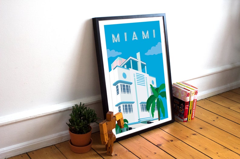 May include: A framed poster with a blue sky and white clouds. The poster features a white art deco building with a palm tree in front of it. The text "MIAMI" is at the top of the poster.