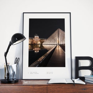 May include: A black and white photograph of the Louvre Museum in Paris, France at night. The iconic glass pyramid is illuminated and reflected in the water. The text "THE LOUVRE PARIS, FRANCE" is at the bottom of the image.