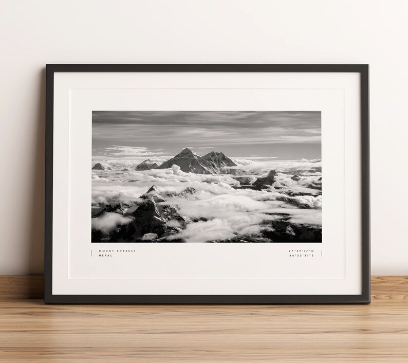 Pu&ograve; includere: Una fotografia in bianco e nero del Monte Everest, la montagna pi&ugrave; alta del mondo, con nuvole che circondano la cima. L'immagine include il testo "MOUNT EVEREST NEPAL 27&deg;59'17" N 86&deg;55'31" E".