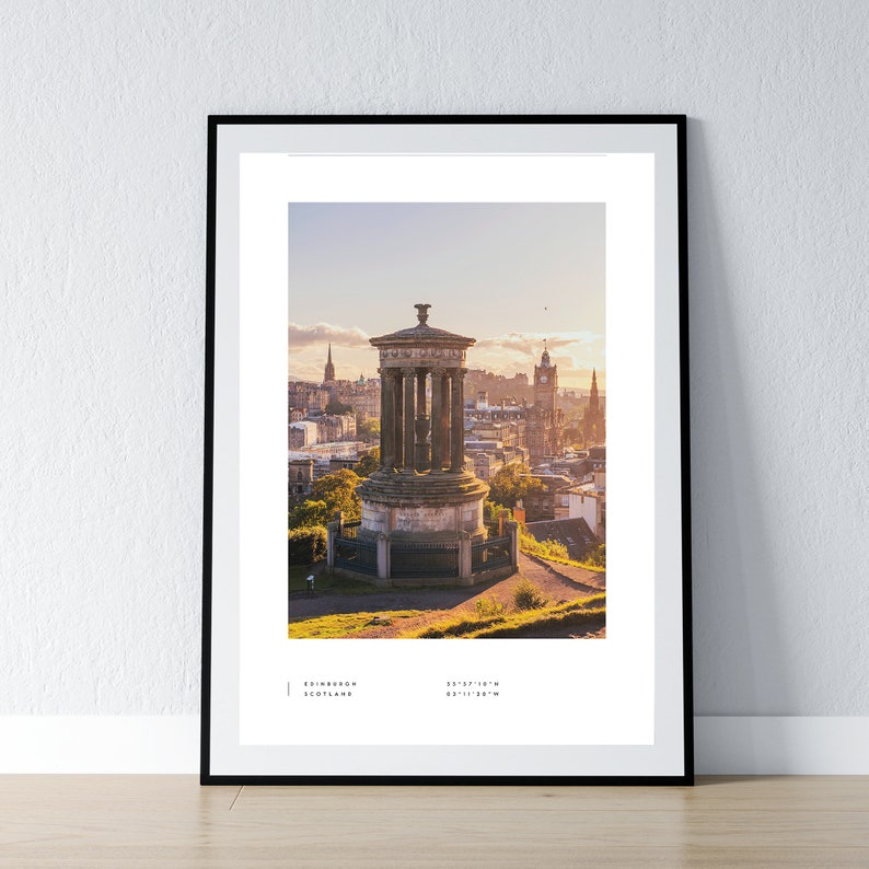 May include: A panoramic view of Edinburgh, Scotland, from atop Calton Hill. The iconic Nelson Monument stands in the foreground, with the city skyline stretching out behind it. The sky is a soft blue with hints of pink and orange from the setting sun.
