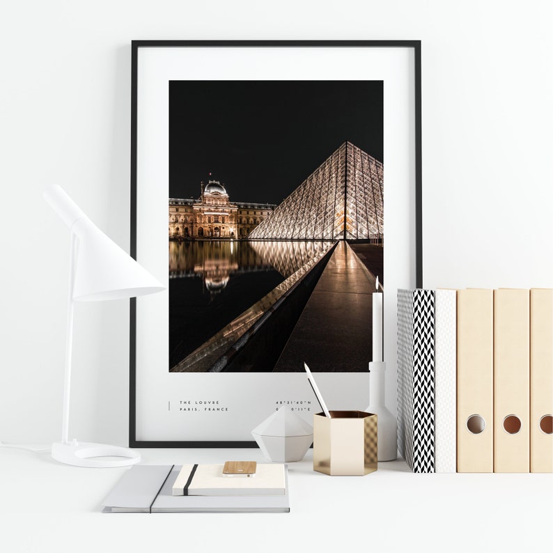 May include: A black and white photograph of the Louvre Museum in Paris, France at night. The iconic glass pyramid is illuminated and reflected in the water. The text "THE LOUVRE PARIS, FRANCE" is printed below the image.