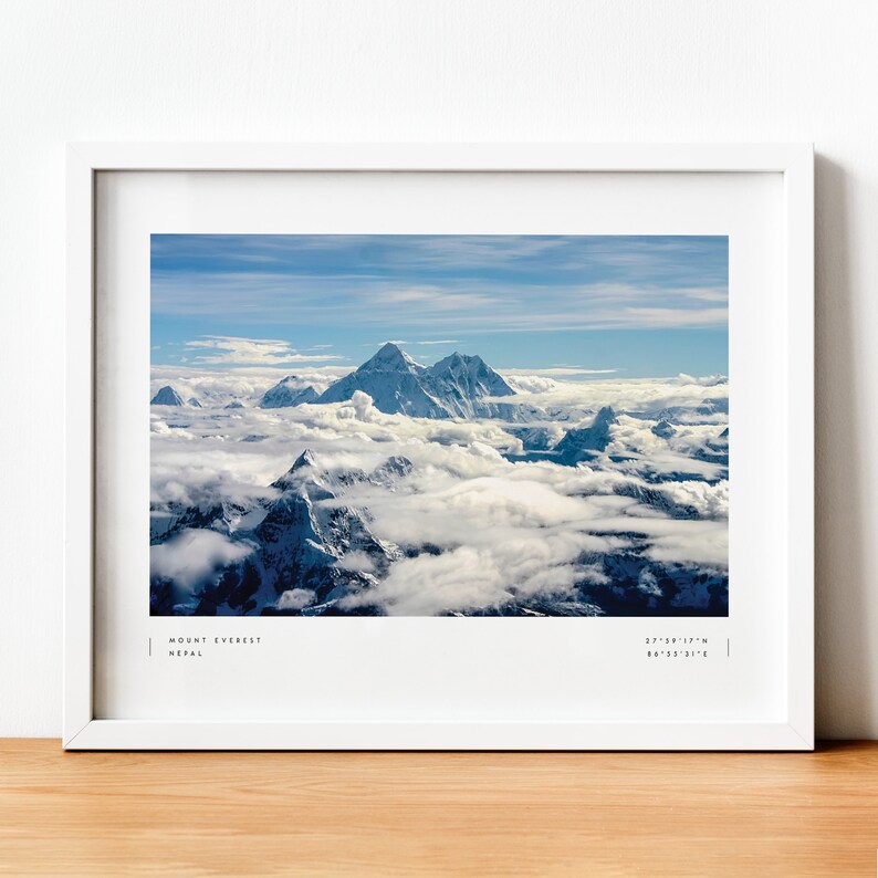 Pu&ograve; includere: Una fotografia incorniciata del Monte Everest, la montagna pi&ugrave; alta del mondo, con cime innevate che si ergono sopra un mare di nuvole. L'immagine &egrave; scattata da una prospettiva aerea, mostrando l'immensit&agrave; dell'Himalaya. Il testo "MOUNT EVEREST NEPAL 27&deg;59'17"N 86&deg;55'31"E" &egrave; stampato nella parte inferiore dell'immagine.