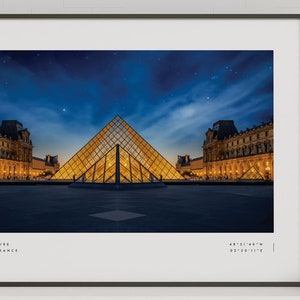 May include: A nighttime photograph of the Louvre Museum in Paris, France. The iconic glass pyramid is illuminated, with the museum building in the background. The sky is dark blue with stars visible.