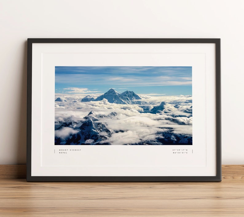 Pu&ograve; includere: Una fotografia incorniciata del Monte Everest, la montagna pi&ugrave; alta del mondo, con cime innevate e nuvole sullo sfondo. Il testo "MOUNT EVEREST NEPAL 27&deg;59'17"N 86&deg;55'31"E" &egrave; stampato sotto l'immagine.