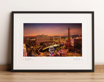 Può includere: Una vista aerea dello skyline di Las Vegas al tramonto, con la replica della Torre Eiffel illuminata in primo piano. Le luci della città brillano sotto, creando una scena vibrante e colorata.