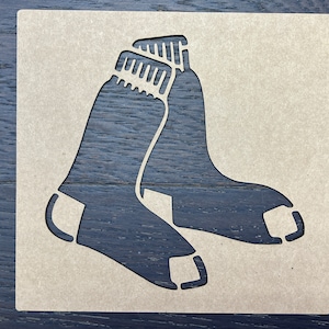 May include: A brown wooden stencil of two socks, resembling the logo of a sports team.