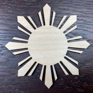 May include: A wooden cutout of the sun with eight rays, resembling the sun on the flag of the Philippines.